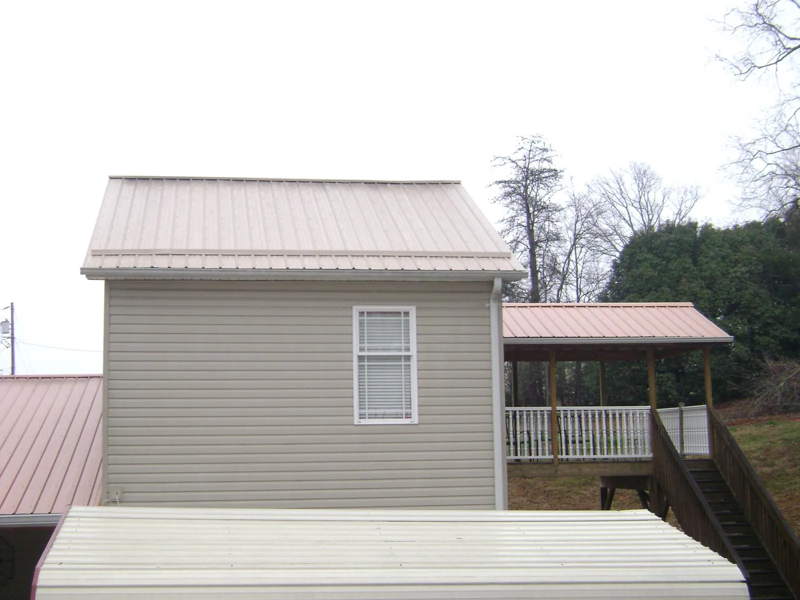 Tan metal roofs on a two story addition and attached porch, from a Roof Replacement job in Pendleton