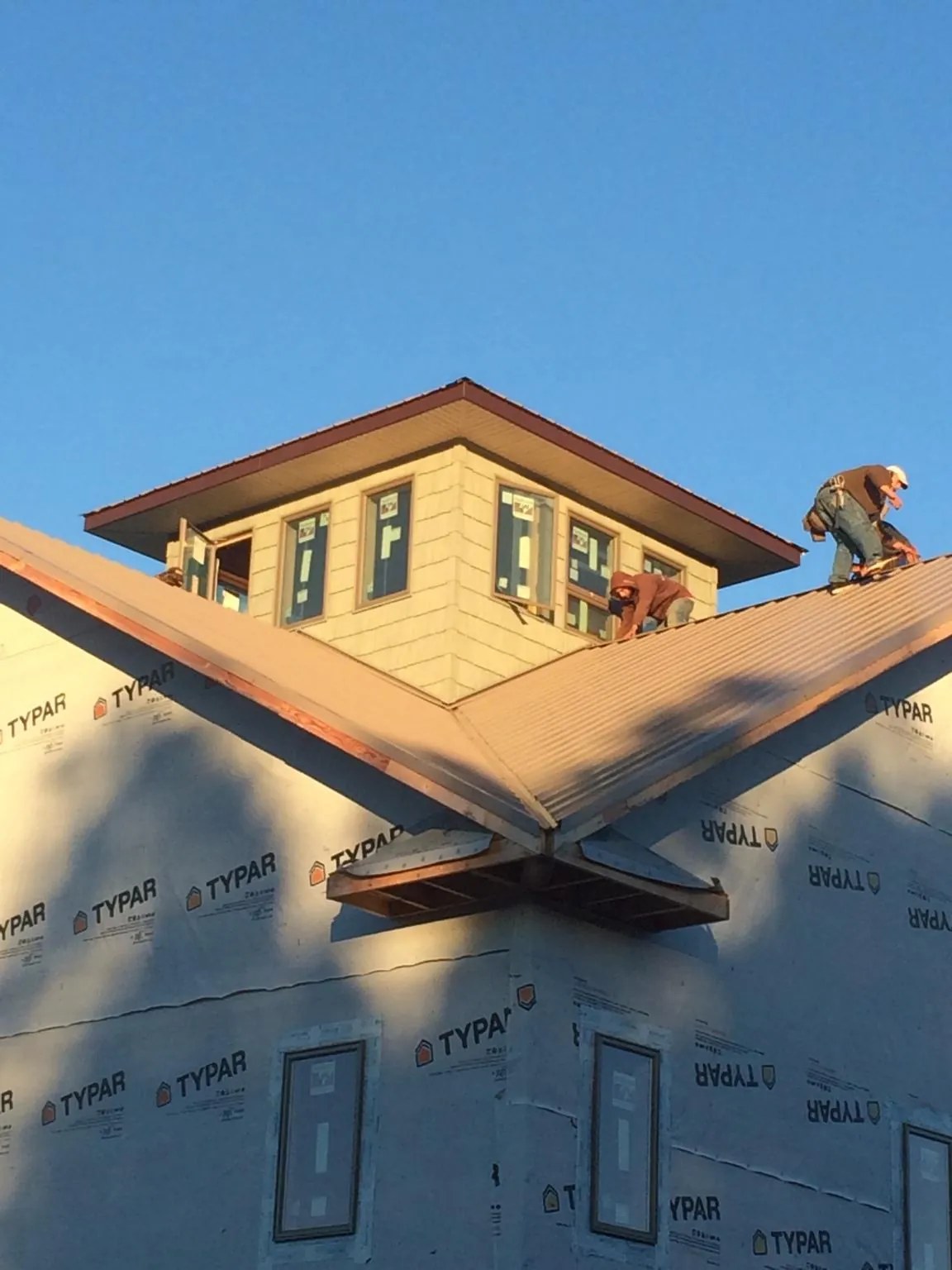 Roofers working around a rooftop cupola on a new metal roof at sunset — Roof Waterproofing in Pendleton by Roofing Brothers